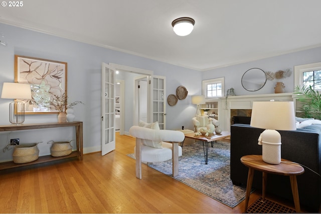436 SE 44th Ave, Portland, OR 97215 - living area featuring wood finished floors, ornamental molding, a tiled fireplace, and french doors
