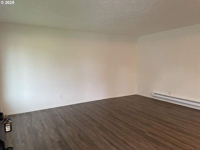 spare room featuring a baseboard heating unit, dark hardwood / wood-style floors, and a textured ceiling