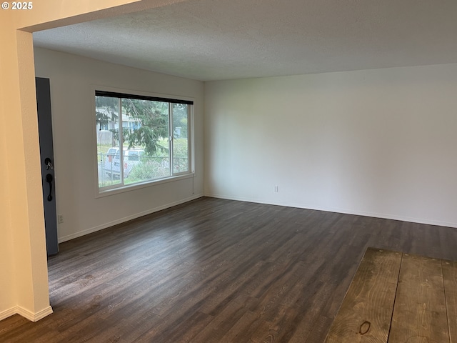 empty room with dark hardwood / wood-style floors and a textured ceiling