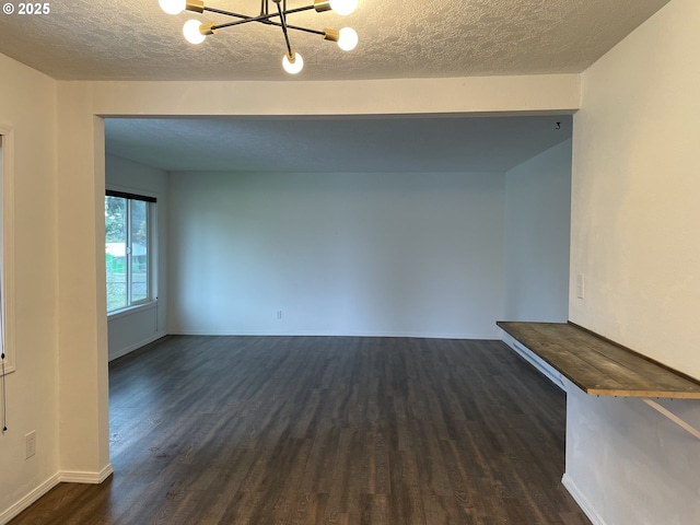 unfurnished room with dark hardwood / wood-style flooring, a notable chandelier, and a textured ceiling