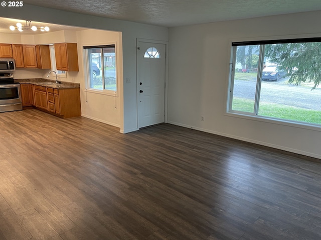 kitchen with sink, dark wood-type flooring, a textured ceiling, and appliances with stainless steel finishes