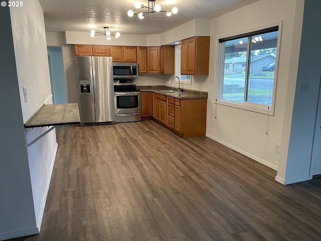 kitchen featuring dark hardwood / wood-style floors, sink, a chandelier, stainless steel appliances, and a textured ceiling