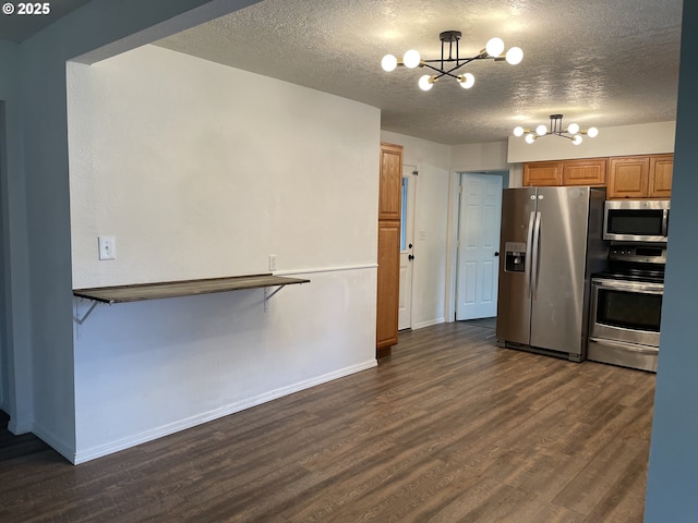 kitchen with a breakfast bar, appliances with stainless steel finishes, dark hardwood / wood-style floors, a notable chandelier, and a textured ceiling