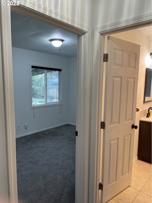 hallway with light tile patterned floors and a textured ceiling