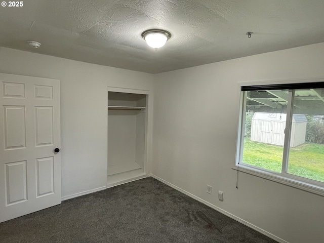 unfurnished bedroom with dark carpet, a closet, and a textured ceiling