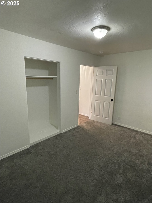 unfurnished bedroom featuring dark carpet, a closet, and a textured ceiling