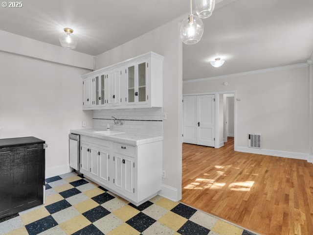 20 NW 16th Ave Unit 8, Portland, OR 97209 - kitchen featuring visible vents, light floors, white cabinetry, tasteful backsplash, and a sink