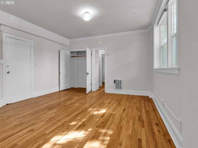 20 NW 16th Ave Unit 8, Portland, OR 97209 - unfurnished bedroom with crown molding, baseboards, light wood-type flooring, and visible vents