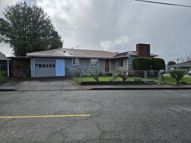 single story home with a gate, a fenced front yard, aphalt driveway, an attached garage, and metal roof