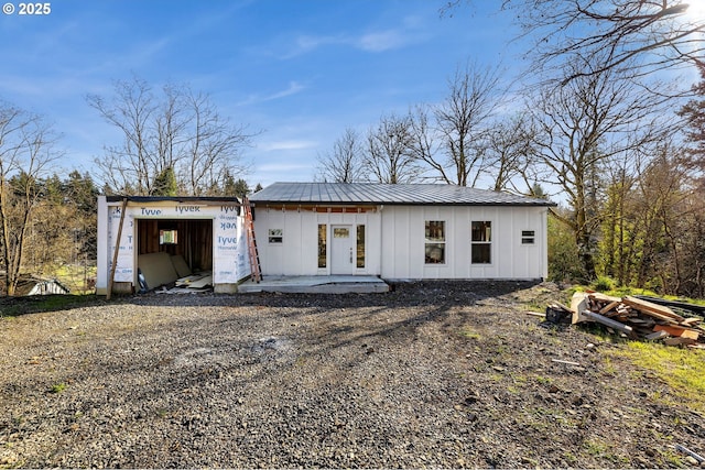 view of front of home featuring a garage, board and batten siding, driveway, and metal roof