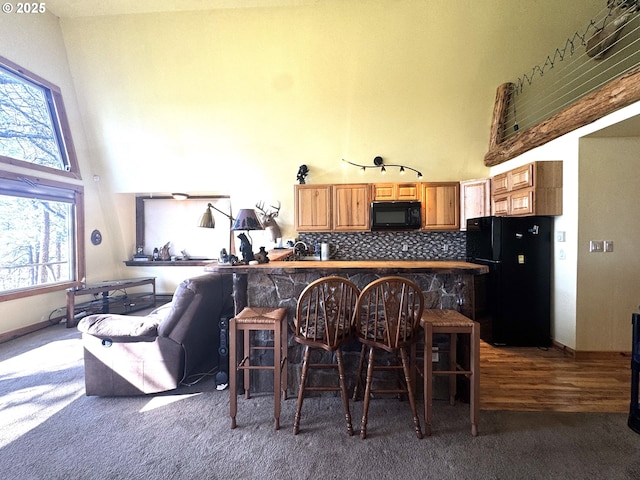 87 Adams Loop Rd, Goldendale, WA 98620 - bar featuring backsplash, black appliances, dark colored carpet, and a towering ceiling