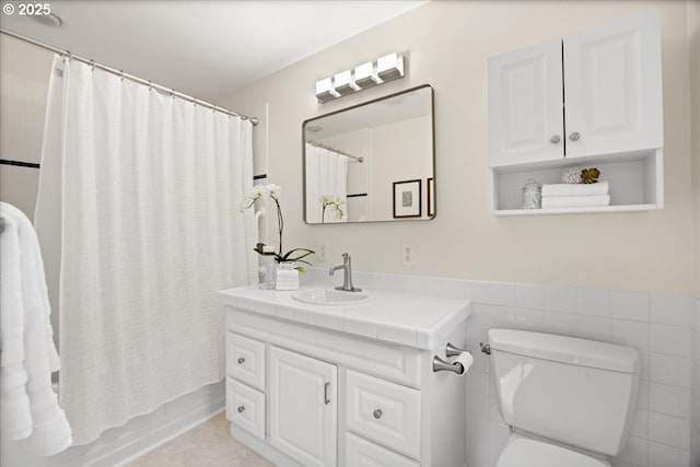 full bath featuring tile walls, shower / bath combo with shower curtain, vanity, and toilet