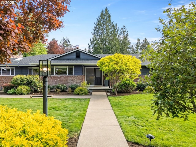 view of front of house featuring brick siding, roof with shingles, and a front lawn