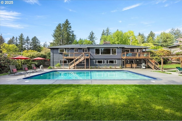 back of property with stairway, a wooden deck, and an outdoor pool
