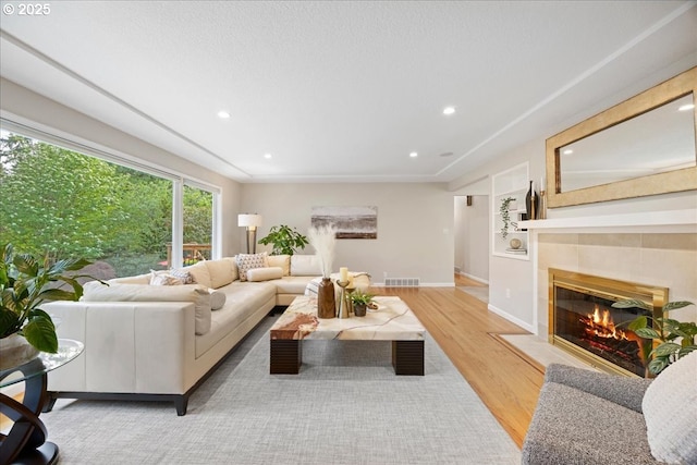 living area featuring recessed lighting, baseboards, wood finished floors, and a tile fireplace