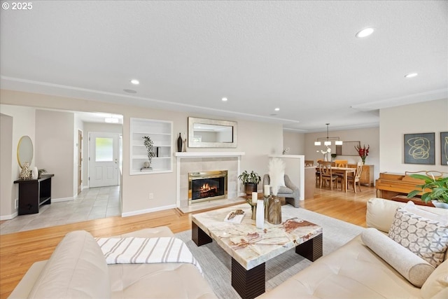 living room featuring recessed lighting, baseboards, a tile fireplace, and light wood-type flooring