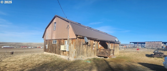 view of side of home featuring metal roof, a gambrel roof, and an outbuilding
