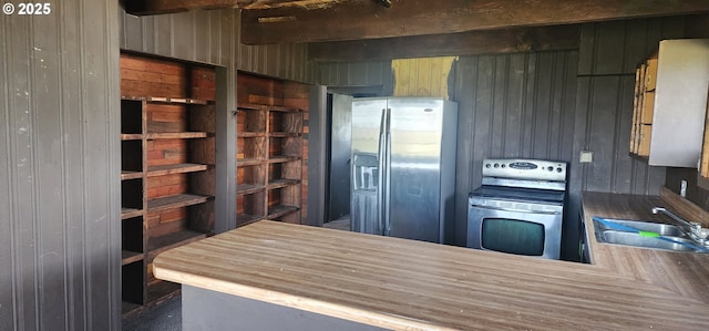 kitchen featuring a sink, stainless steel appliances, and wooden walls