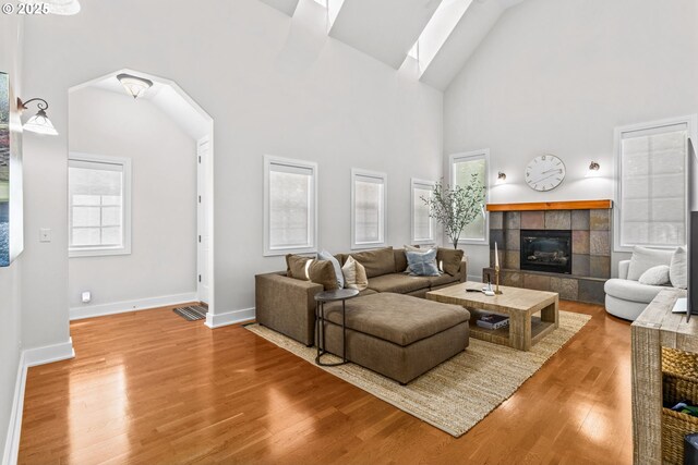 465 Covey Ln, Eugene, OR 97401 - living area featuring wood finished floors, a tiled fireplace, high vaulted ceiling, baseboards, and arched walkways