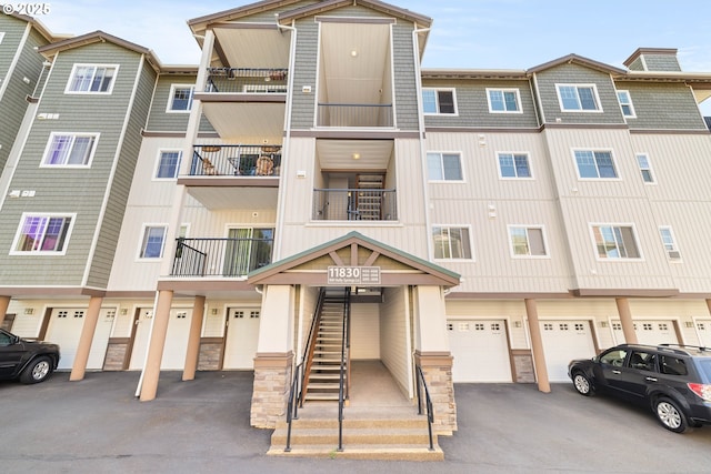 11830 NW Holly Springs Ln Unit 406, Portland, OR 97229 - view of property featuring an attached garage, driveway, and stairway