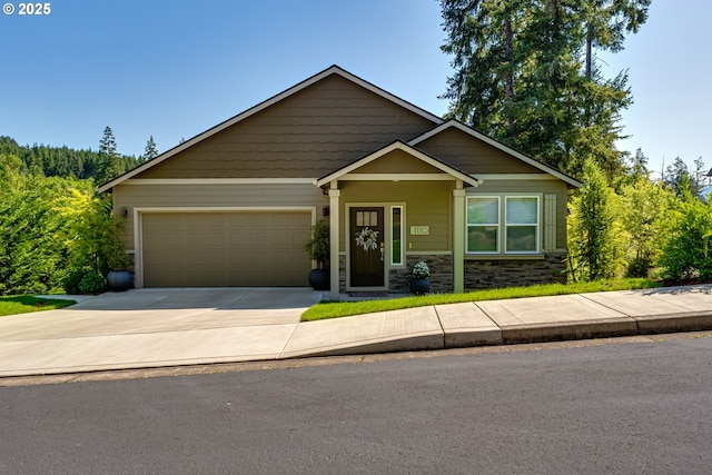 craftsman-style home featuring an attached garage, driveway, and stone siding