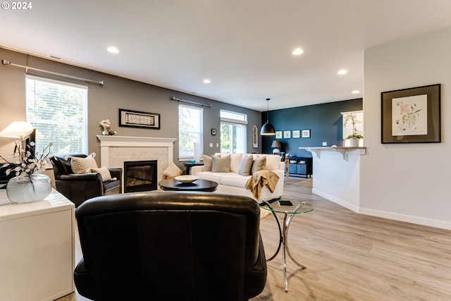 living area featuring a brick fireplace, light wood-style floors, recessed lighting, and baseboards