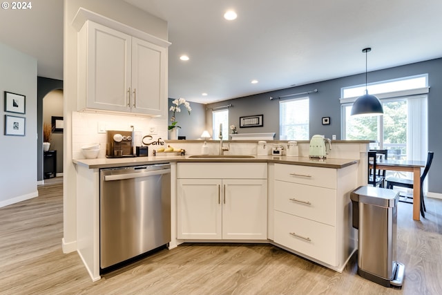 kitchen featuring dishwasher, a sink, arched walkways, light wood-style flooring, and recessed lighting