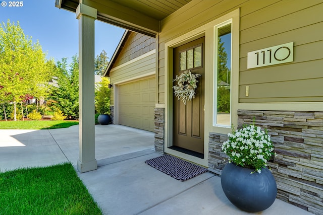 property entrance with stone siding, driveway, and a garage