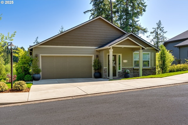 craftsman-style house featuring an attached garage, stone siding, and driveway
