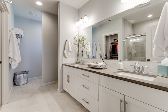 full bath featuring a stall shower, a walk in closet, double vanity, baseboards, and recessed lighting