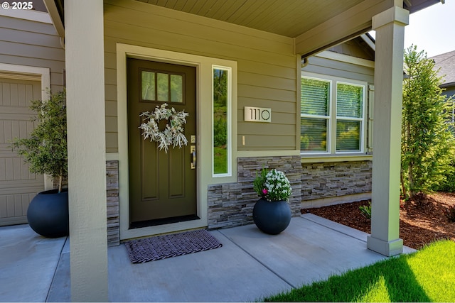 view of exterior entry featuring stone siding and a porch