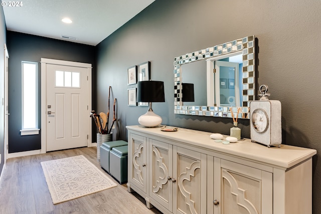 foyer entrance with light wood-style flooring and baseboards