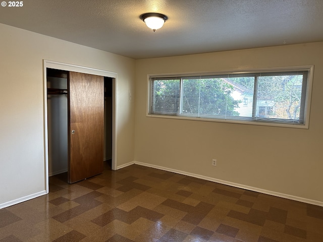 unfurnished bedroom with multiple windows, a closet, and a textured ceiling