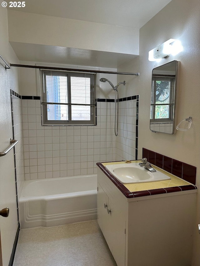 bathroom featuring vanity, a healthy amount of sunlight, and tiled shower / bath