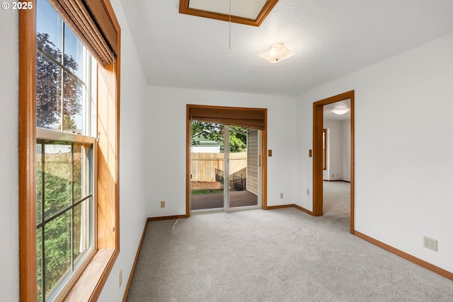 spare room with attic access, carpet, and baseboards