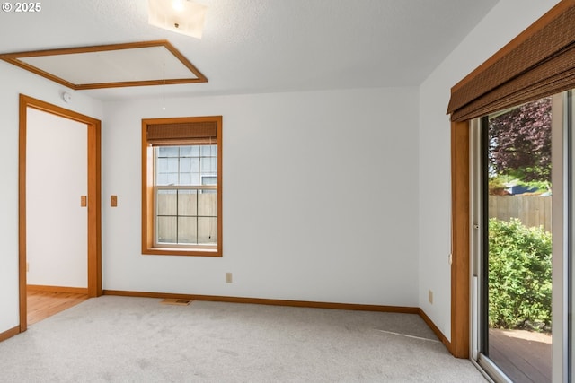 unfurnished room featuring attic access, light carpet, baseboards, and a smoke detector