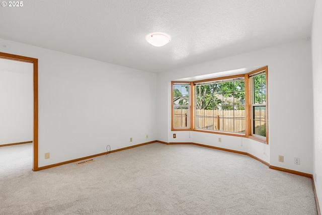unfurnished room with carpet, baseboards, and a textured ceiling