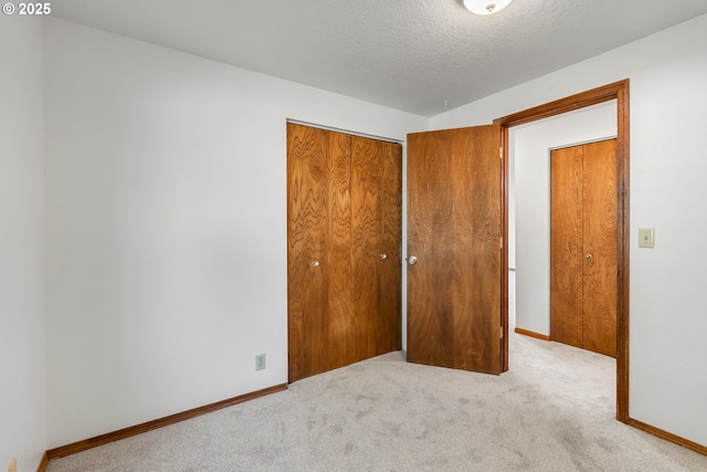 unfurnished bedroom featuring carpet floors, a closet, baseboards, and a textured ceiling
