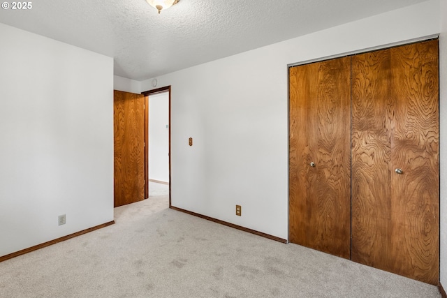 unfurnished bedroom with carpet flooring, baseboards, a closet, and a textured ceiling