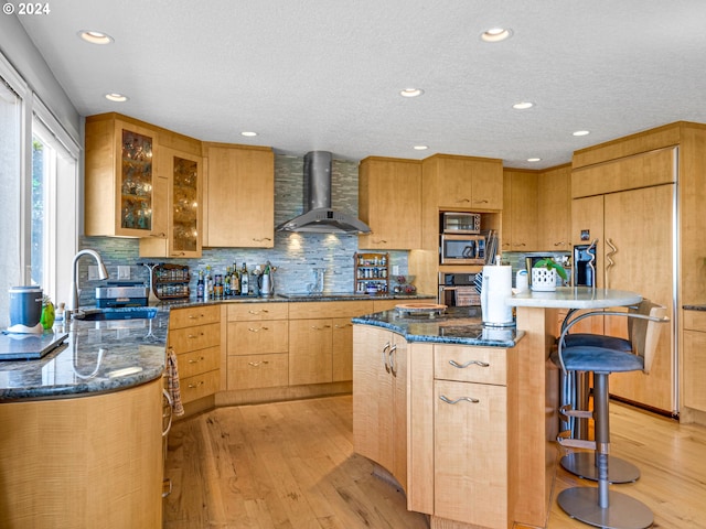 89610 Sea Breeze Dr, Warrenton, OR 97146 - kitchen featuring a sink, light wood-type flooring, a breakfast bar area, wall chimney exhaust hood, and appliances with stainless steel finishes