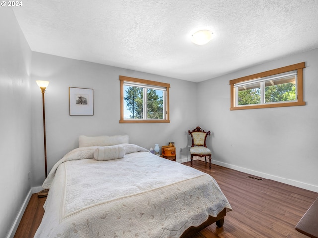89610 Sea Breeze Dr, Warrenton, OR 97146 - bedroom with baseboards, visible vents, a textured ceiling, and wood finished floors
