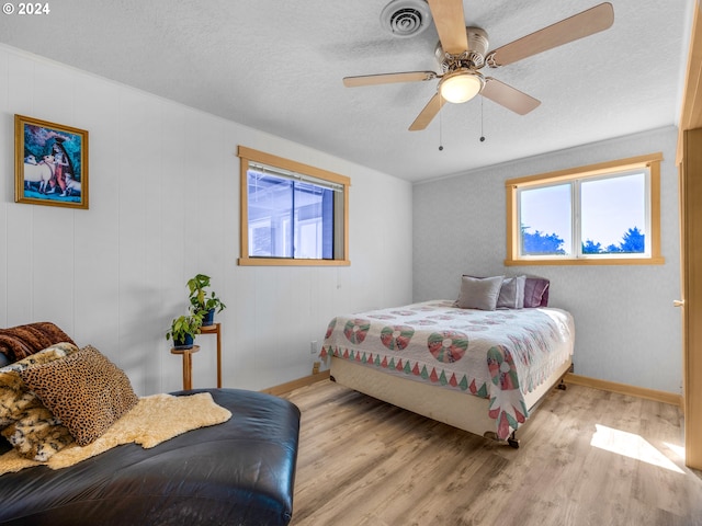 89610 Sea Breeze Dr, Warrenton, OR 97146 - bedroom featuring wood finished floors, a ceiling fan, a textured ceiling, visible vents, and baseboards