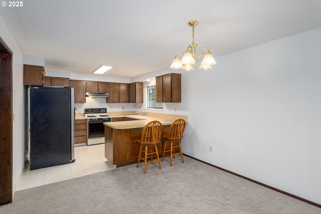 kitchen with a sink, freestanding refrigerator, an inviting chandelier, a peninsula, and white gas range