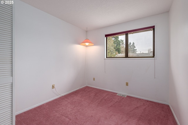 carpeted empty room with baseboards, visible vents, and a textured ceiling