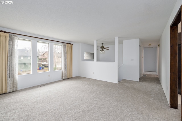 unfurnished living room with light colored carpet and a ceiling fan