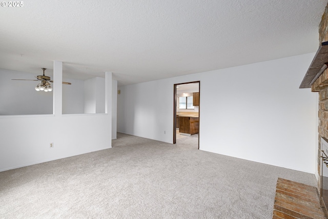 unfurnished living room featuring light carpet, a fireplace, a textured ceiling, and ceiling fan