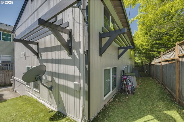 view of side of home with a lawn and fence