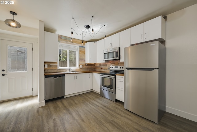 kitchen featuring appliances with stainless steel finishes, white cabinetry, baseboards, decorative backsplash, and dark wood-style floors