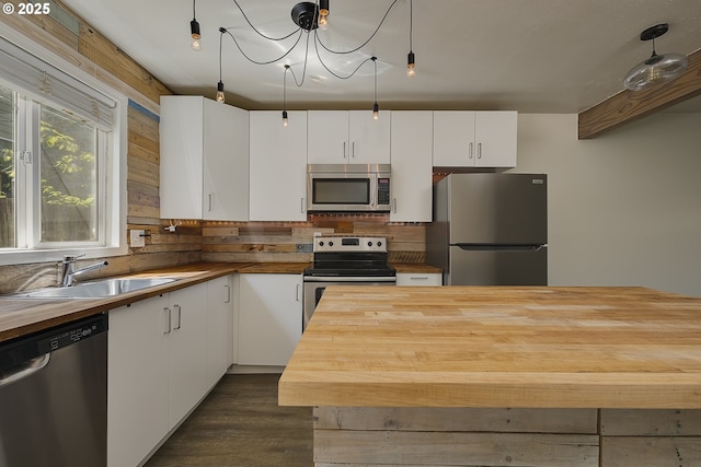 kitchen with a sink, wood counters, stainless steel appliances, white cabinetry, and tasteful backsplash