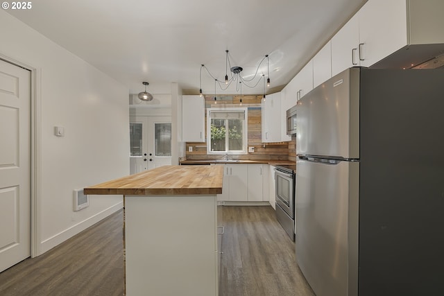 kitchen with an inviting chandelier, wood finished floors, white cabinetry, wood counters, and stainless steel appliances